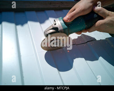 Il master taglia il foglio di metallo con una sega circolare. Foto Stock