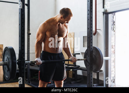 Muscolare di un giovane uomo che lavora fuori con barbell in sport club Foto Stock