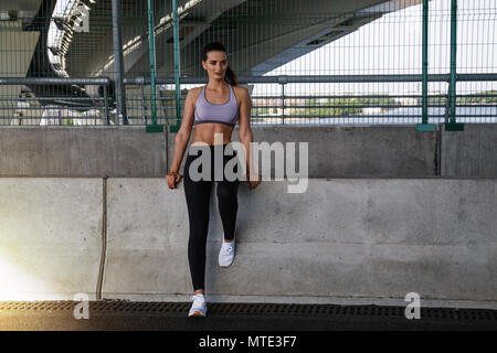 Donna giovane atleta appoggiato su di una parete durante gli esercizi Foto Stock