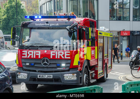 Un motore fire appartenenti al London Vigili del Fuoco la guida attraverso Hammersmith con luci blu e sirena rimbombava. Foto Stock