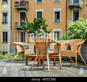 Tavoli e sedie in legno su una terrazza esterna in un quartiere residenziale durante l'estate. Foto Stock