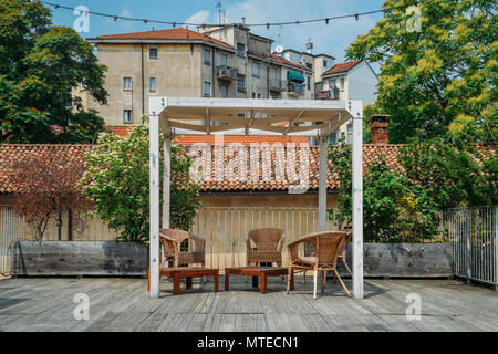 Tavoli e sedie in legno su una terrazza esterna in un quartiere residenziale durante l'estate. Foto Stock