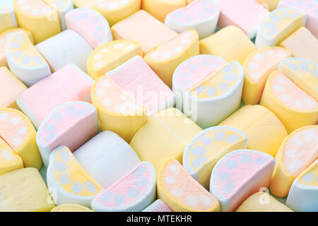 Colorato dolci marshmallows. Giallo, blu e rosa pastello alla moda i colori di sfondo o texture di mini marshmallows. Vista superiore, close-up. Foto Stock