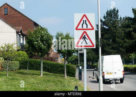 Inglese il traffico stradale triangolare di cartelli di avviso per la strada si restringe e zebra crossing in una strada residenziale di Poole, Dorset, Regno Unito Foto Stock