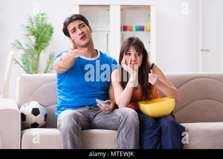 Giovane uomo guardando la partita di calcio con la moglie a casa Foto Stock