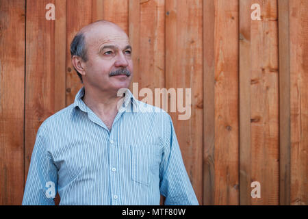 Ritratto di fiducioso uomo di mezza età che cercano riposo su sfondo di legno Foto Stock