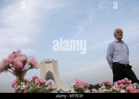 TEHRAN, IRAN - 7 maggio 2018 la torre Azadi dietro rosa e bianco geranium cranesbill fiori, stagione primavera persone godendo da visitare Foto Stock