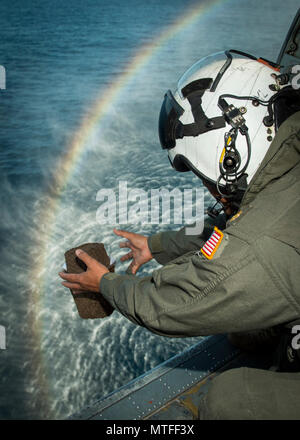 Lt. La Cmdr. Juan Cometa, un cappellano della marina militare assegnato al comandante, elicottero mare ala di combattimento del Pacifico, conduce una sepoltura in mare da un HH-60H Seahawk elicottero elicottero da combattimento del mare Squadron (HSC) 85 vicino a San Diego, California, 22 aprile 2017. HSC-85 fornisce dedicato ala rotante di supporto a U.S. Il Comando Operazioni Speciali in tutto il mondo. Foto Stock