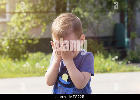 Il bambino piange di risentimento, Sob sobbingly che copre il viso con le mani Foto Stock