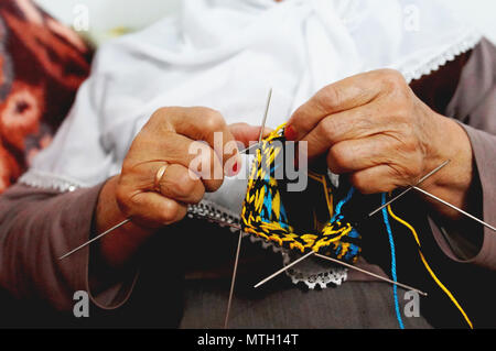 Close up della vecchia donna mani della maglieria colorata lana calza con aghi di tessitura Foto Stock