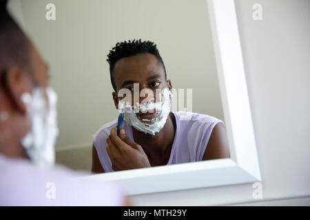 L'uomo la rasatura sotto lo specchio Foto Stock