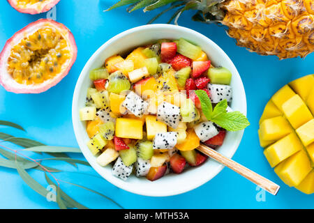 Insalata di frutta tropicali e frutti esotici su sfondo blu. Una sana insalata di frutta. Frutti tropicali sul blu. Vista superiore Foto Stock
