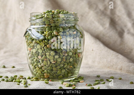 Materie di piselli verdi in un barattolo di vetro sulla tovaglia homespun, close-up, il fuoco selettivo. Alcuni di questi testi lo spazio per la vostra iscrizione. Organico - proteica. Ingredie perfetto Foto Stock