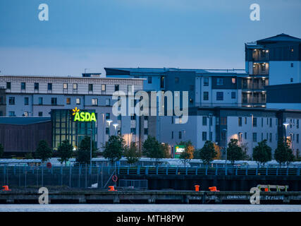 Vista delle luci al neon accese del supermercato Asda a Newhaven da di fronte al porto di Leith di notte Foto Stock