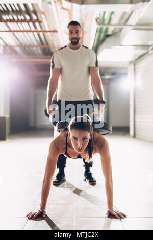 Giovane donna muscolare facendo attraversare allenamento con personal trainer presso il garage palestra. Foto Stock