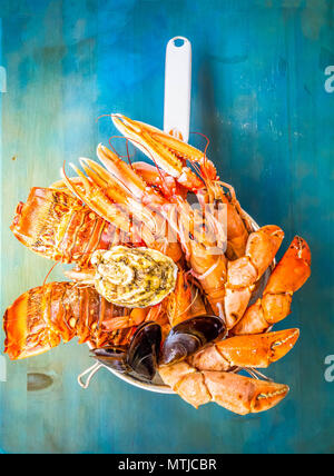 Piatti a base di frutti di mare freschi di catture di scampi e granchi e langostines su sfondo blu, dai toni rétro Foto Stock