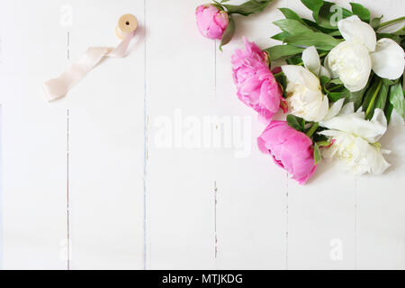 Elegante stock photo. Nozze femminile o tabella di compleanno con composizione floreale. Bianco e rosa fiori di peonie e bobina di nastro di seta. Bianco Foto Stock