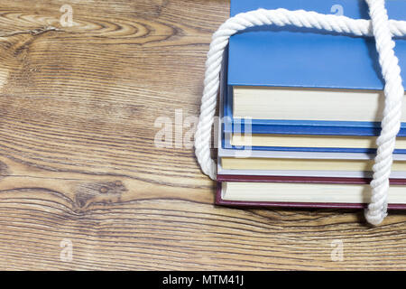 Pila di libri legato su sfondo di legno Foto Stock