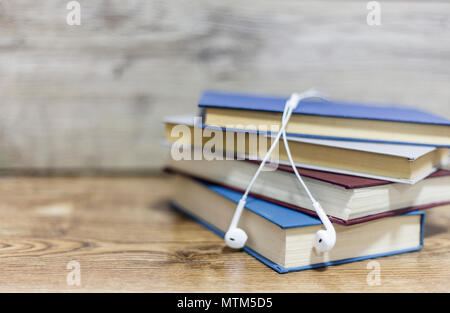 Sfocato quattro libri e auricolare su un tavolo di legno Foto Stock