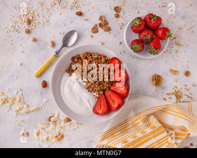 Il Granola gustosi con yogurt e fragole fresche sulla tavola bianco Foto Stock