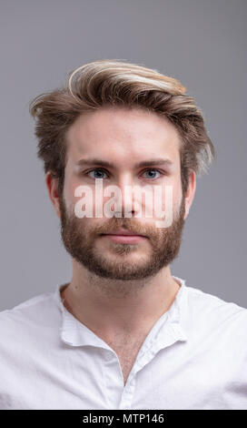 Close-up studio shot ritratto di un bel giovane uomo barbuto pensando ai futuri contro sfondo beige per spazio di copia Foto Stock