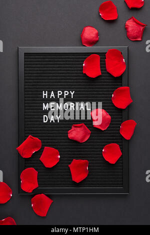 Letterboard nero bianco con lettere in plastica con citazione Happy Memorial Day e petali di rosa su sfondo nero. Foto Stock