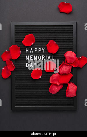 Letterboard nero bianco con lettere in plastica con citazione Happy Memorial Day e petali di rosa su sfondo nero. Foto Stock