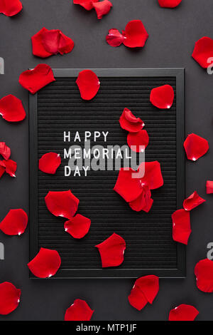 Letterboard nero bianco con lettere in plastica con citazione Happy Memorial Day e petali di rosa su sfondo nero. Foto Stock