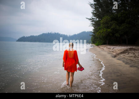 Una donna bionda passeggiate lungo la Spiaggia di Damai Laut Resort in Malaysia. Foto Stock