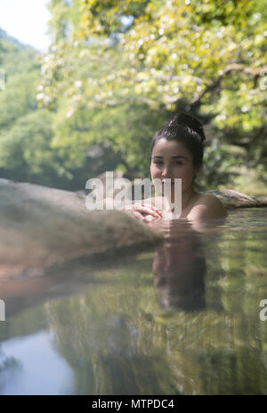 Donna di balneazione in outdoor onsen / primavera calda a Myoken Ishikaraso, Kirishima, Kyushu, Giappone Foto Stock