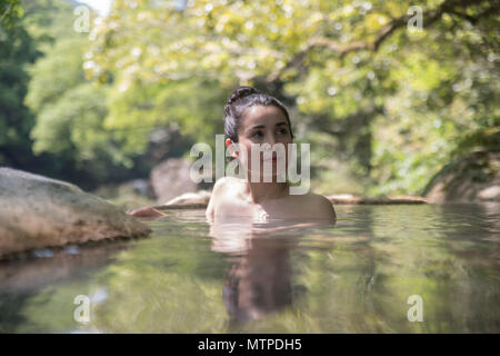 Donna di balneazione in outdoor onsen / primavera calda a Myoken Ishikaraso, Kirishima, Kyushu, Giappone Foto Stock