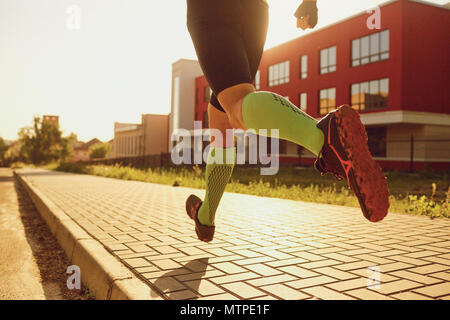 Gambe di atletica di uomini che corre lungo la strada della citta'. Foto Stock