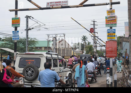 Pondicherry, India - 17 Marzo 2018: il traffico e i pedoni streaming su un passaggio a livello vicino alla stazione dopo un treno passeggeri ha appena superato Foto Stock