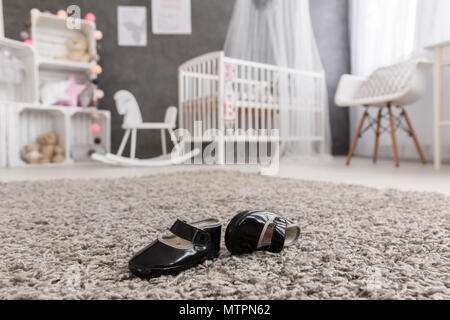 Colpo di nero scarpe bambino posa su un tappeto in un vivaio Foto Stock