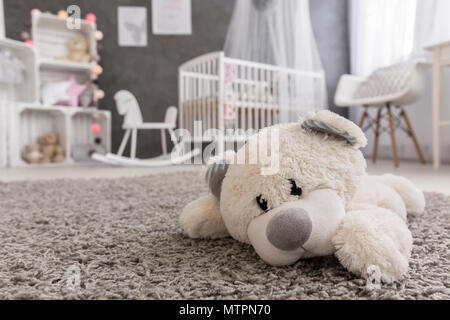Inquadratura di un orso di peluche posa su un tappeto in un accogliente Baby girl room Foto Stock