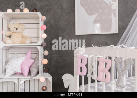 Inquadratura di un presepe e alcune caselle in grigio e bianco baby room Foto Stock