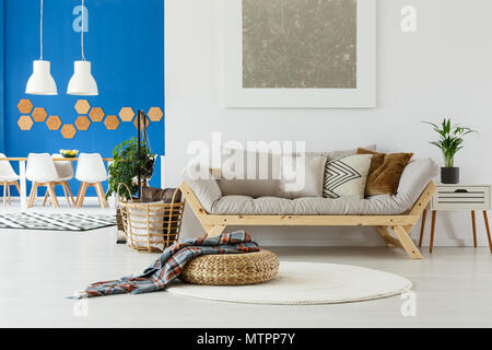 Naturale nel design interno contemporaneo di un piano aperto appartamento con spazio da pranzo, divani beige, piante e parete blu Foto Stock