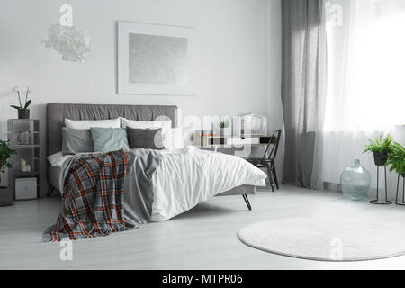 Finestra con il grigio e il bianco tende in spaziosa camera da letto con letto matrimoniale Foto Stock