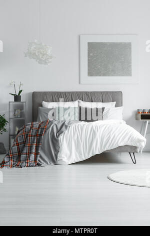 Letto king size con morbidi bedheads grigio in piedi in camera bianca Foto Stock