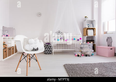 Spaziosa camera da letto della bambina. Pavimento in legno con tappeti,  culla di bianco e decorazioni colorate Foto stock - Alamy