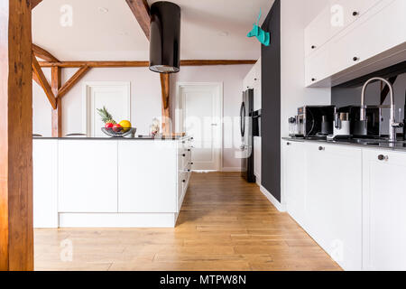 Camere spaziose in bianco e nero la cucina con frutti nella ciotola sul bancone della cucina isola e decor di colore blu sul muro nero Foto Stock