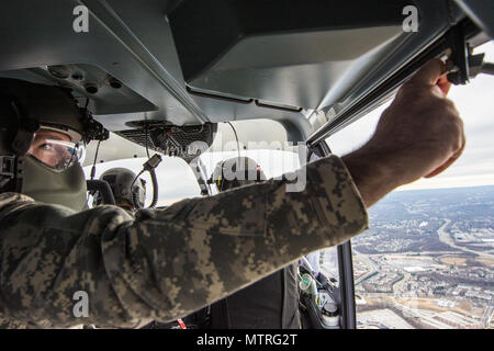 Stati Uniti Army Sgt. Andrew Ricken, un UH-72A Lakota capo equipaggio con distacco 1, Alfa Company, 1-244, Sicurezza aerea e battaglione di supporto, D.C. La Guardia nazionale, raggiunge per chiudere la porta dell'elicottero al di sopra di Washington D.C., Gennaio 18, 2017. L'equipaggio del UH-72A sono state sostenendo la 58th inaugurazione presidenziale dove Trump sarà giurato-in come il quarantacinquesimo Presidente degli Stati Uniti. 7.500 guardie nazionali da 44 membri, tre territori e il Distretto di Columbia assegnato alla Joint Task Force D.C. sono per fornire la gestione del traffico, la gestione della folla, la sicurezza e la logistica sup Foto Stock