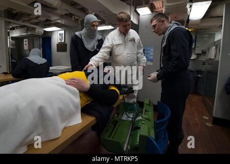 Oceano atlantico (25 aprile 2017) - Royal Navy Chief Petty Officer Chaz Charlesworth, centro, esamina le cure mediche fornite da uno specialista della logistica di 2a classe di Kevin Amador, sinistra e Hospital Corpsman 2a classe Alex Penegar a bordo della USS Carney (DDG 64) durante un quartier generale trapanare come la nave partecipa a bandiera Officer Sea allenamento Aprile 25, 2017. Carney, un Arleigh Burke-class guidato-missile distruttore, distribuita a Rota, Spagna, sta conducendo la sua pattuglia di terzi negli Stati Uniti Sesta flotta area di operazioni a sostegno degli Stati Uniti per gli interessi di sicurezza nazionali in Europa. Foto Stock