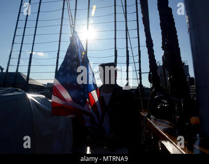 BOSTON (GEN. 21, 2017) di Boatswain Mate 2a classe Michael San Germain in posa per una foto prima che egli di paranchi a bandiera che è stato acquistato da un visitatore a bordo di vecchie Ironsides. Il morale, il benessere e la ricreazione comitato vende bandiere e il comando challange monete a bordo della nave durante gli orari di visita. (U.S. Navy Foto di artigliare il compagno del 3° di classe Erin giovenco/rilasciato) Foto Stock