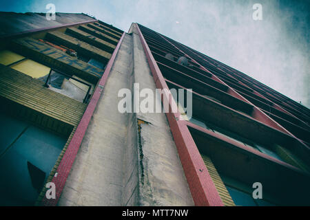 Vista dal basso di un calcestruzzo vecchio e sporco di età home edificio con il rosso e il giallo i dettagli. Foto Stock