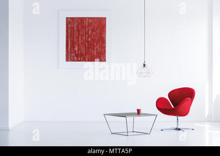 Ceramica rossa tazza da caffè in piedi sul tavolo di metallo accanto alla poltrona moderna Foto Stock