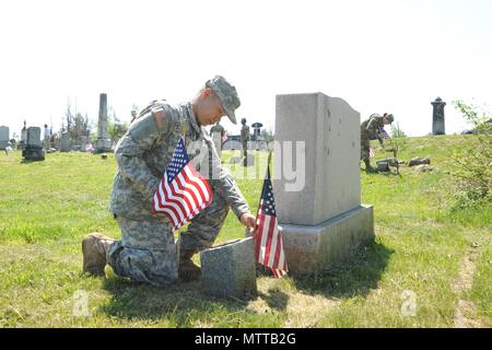 La 543rd Composite Supply Company è un'unità logistica all'interno del 548th Combat Sustainment Support Battalion, assegnata alla 10th Mountain Division Sustainment Brigade a Fort Drum, New York. Un soldato partecipa a piantare bandiere nei cimiteri nell'area dei villaggi perduti il 24 maggio in osservanza del Memorial Day. L'immagine d'archivio documenta i membri dell'unità onorando i veterani attraverso la decorazione delle tombe. Foto Stock