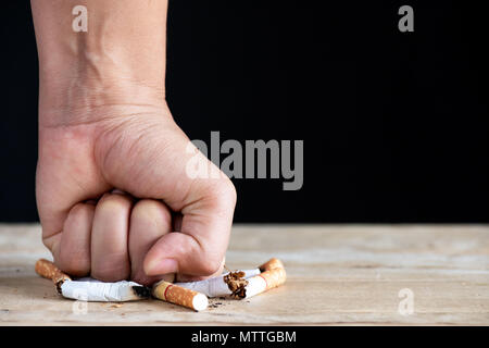 Celebra la Giornata Mondiale senza tabacco, 31 maggio. Smettere di fumare. Close up man mano la frantumazione e la distruzione di sigarette su sfondo nero. Foto Stock
