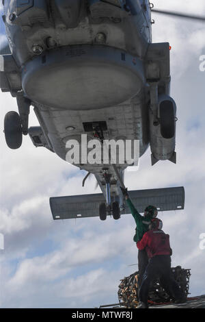 170130-N-RM689-359 OCEANO PACIFICO (GEN. 30, 2017) Aviation Electronics tecnico di terza classe Kruegar Giacobbe (anteriore), da Seattle, Washington, attribuisce il gancio ad un MH-60R Sea Hawk elicottero attaccato ad un elicottero Maritime Strike Squadron 78 mentre Aviation Ordnanceman 1a classe Nick Gravesande, da Tecate, Messico, lo trattiene stabile durante un esercizio pratico per un futuro di rifornimento verticale in mare sul ponte di volo di Arleigh Burke-class guidato-missile destroyer USS Wayne E. Meyer (DDG 108). Wayne E. Meyer è su un regolarmente programmati Pacifico occidentale di implementazione con la Carl Vinson Carrier Foto Stock