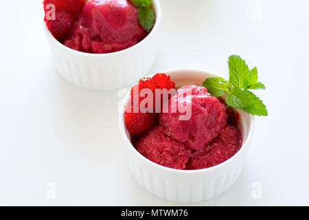 Frutta sorbetto di fragole con la menta nella ciotola di legno bianco sullo sfondo. Foto Stock